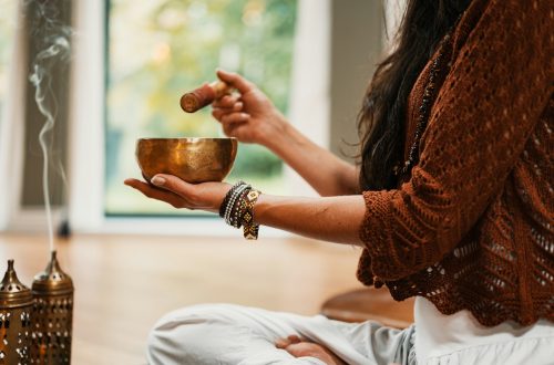woman in brown knit sweater holding brown ceramic cup